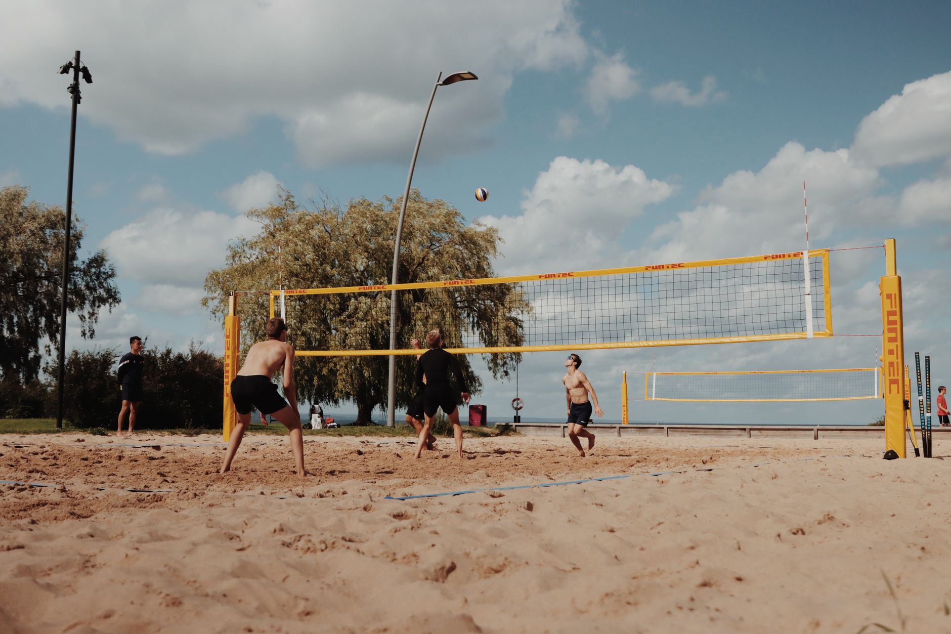 Players competing in beach volleyball in the UK on a sand court