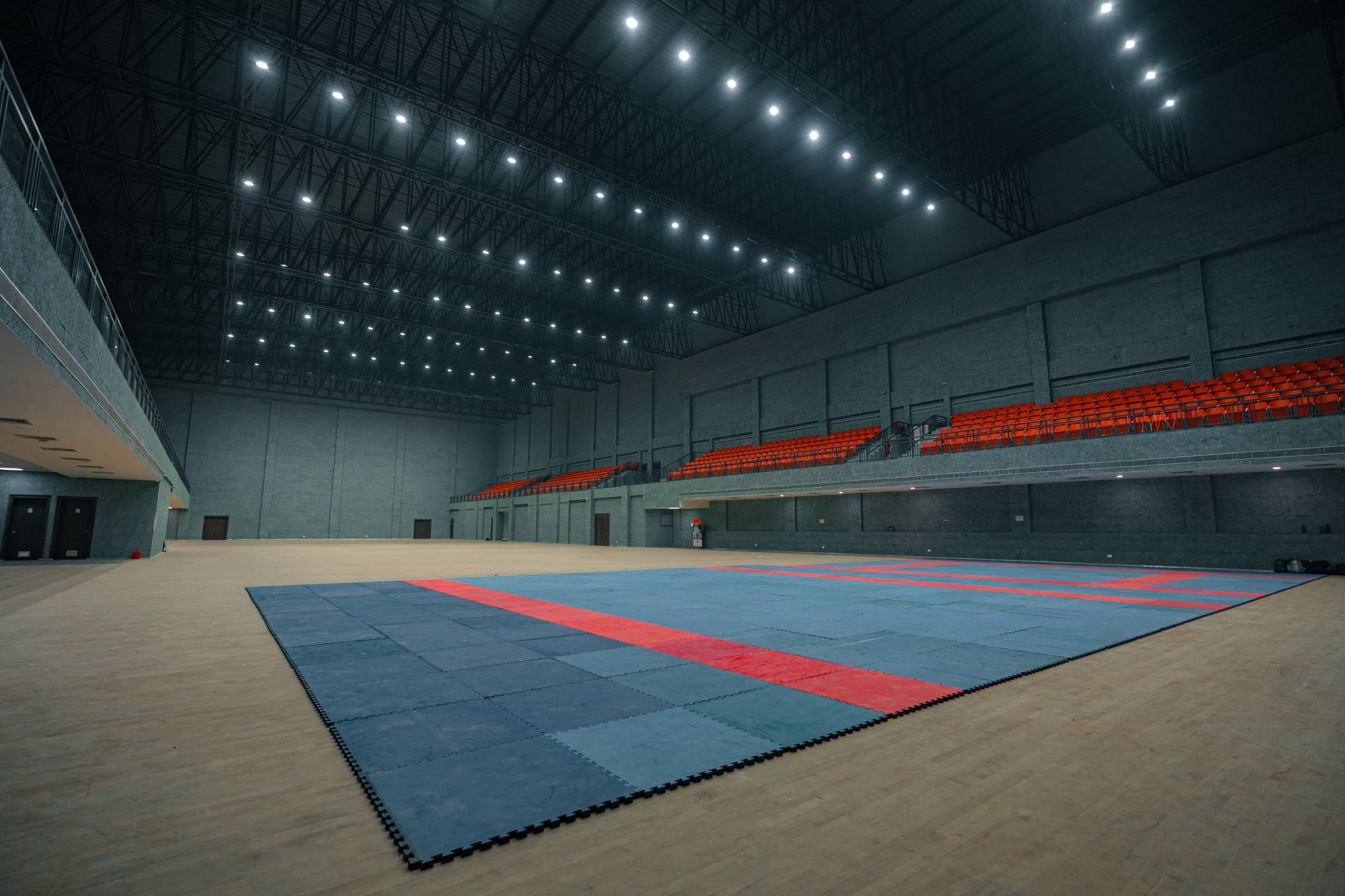 Wide shot of a modern indoor multi-sport complex UK with multiple courts lit for training